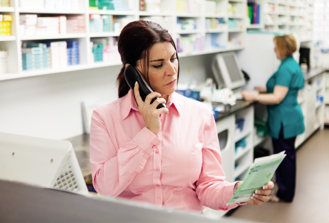 pharmacist looking at prescription whilst on phone