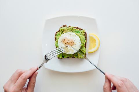 A small plate with avocado on toast and a poached egg on it