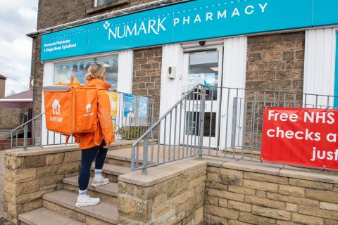 A Just Eat delivery lady entering a Rowlands Pharmacy