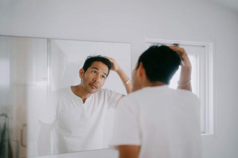 Young man inspecting his hair in the mirror